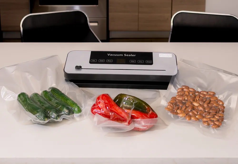 Máquina para empaque al vacío con verduras y almendras empacadas en una cocina