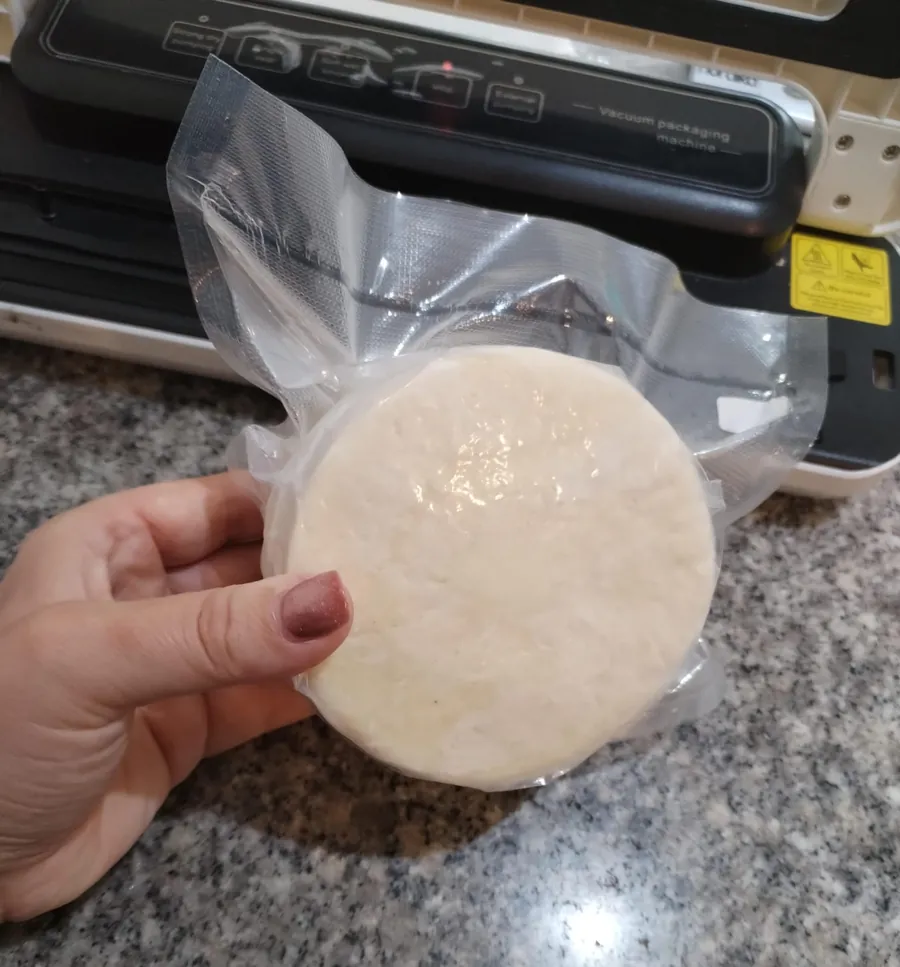 Persona sosteniendo una pieza empacada al vacío junto a la máquina